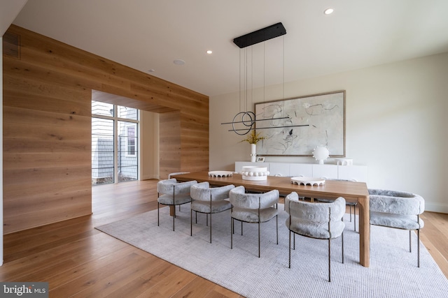 dining room featuring wood walls, recessed lighting, and wood finished floors