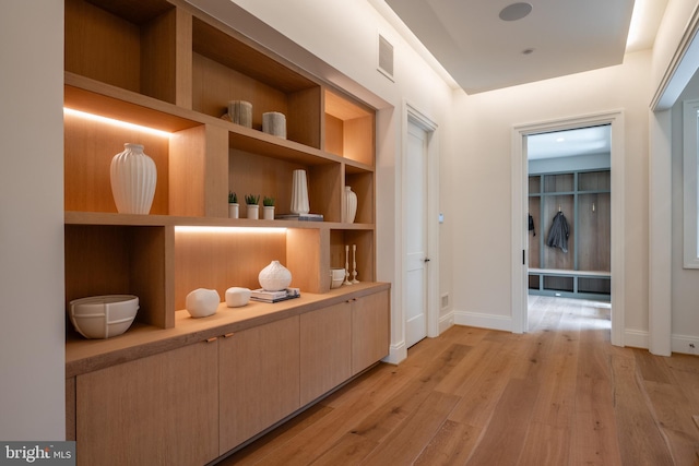 hallway with baseboards, visible vents, and light wood-type flooring