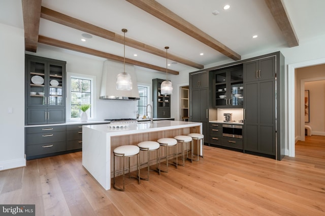 kitchen featuring a kitchen breakfast bar, beamed ceiling, light countertops, and light wood-style floors