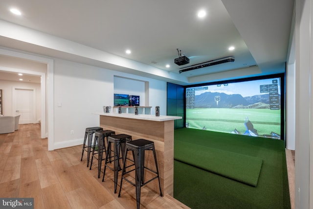 interior space featuring golf simulator, light wood finished floors, baseboards, a raised ceiling, and recessed lighting