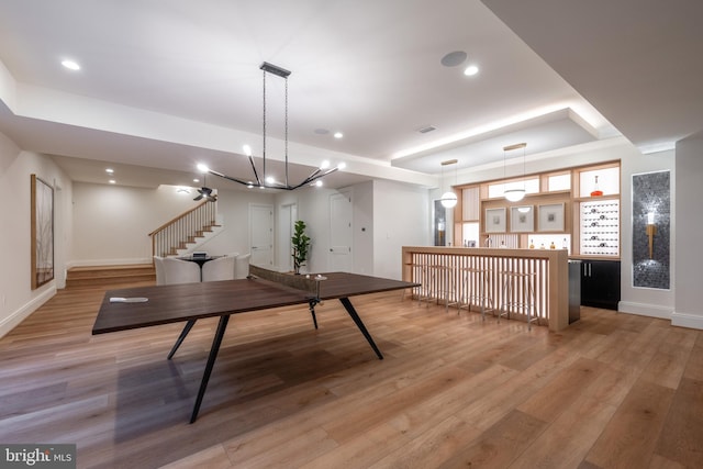 playroom with a tray ceiling, light wood-style floors, baseboards, and recessed lighting
