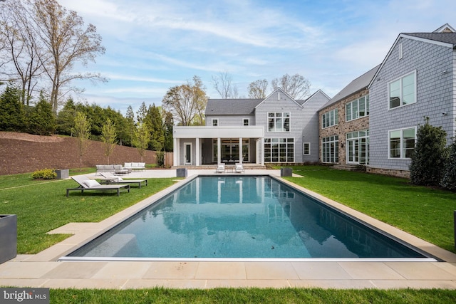 rear view of property featuring a lawn, a patio area, and an outdoor pool