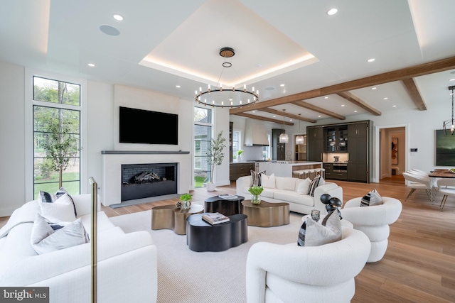 living room featuring light wood-style flooring, recessed lighting, a chandelier, beamed ceiling, and a fireplace