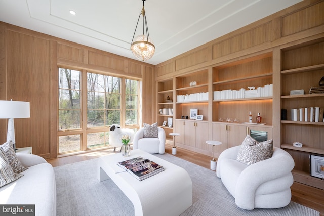 living area featuring wood finished floors, wood walls, and built in shelves