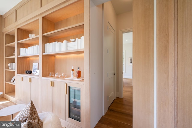interior space featuring built in shelves, wine cooler, a dry bar, and wood finished floors