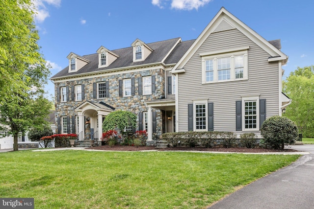colonial inspired home with stone siding and a front lawn