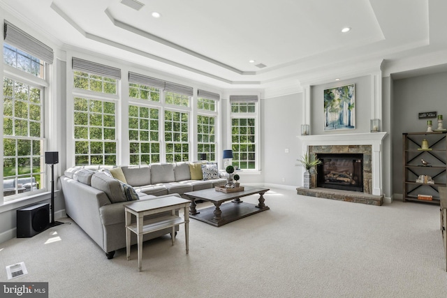 carpeted living area featuring a tray ceiling, a fireplace, baseboards, and visible vents