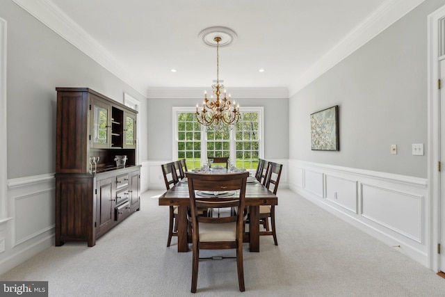dining room featuring a wainscoted wall, light carpet, crown molding, a decorative wall, and a chandelier