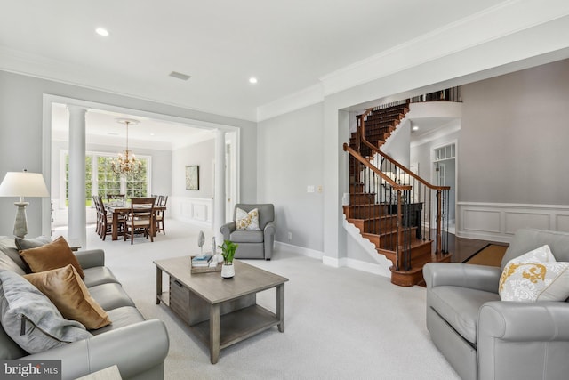 carpeted living room featuring stairs, decorative columns, a notable chandelier, ornamental molding, and recessed lighting