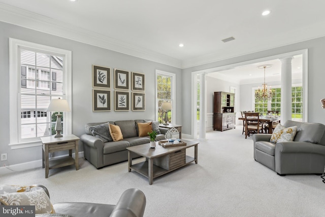 carpeted living area with ornamental molding, a healthy amount of sunlight, baseboards, and ornate columns