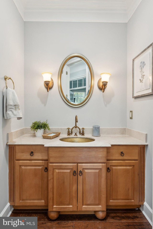 bathroom featuring vanity, ornamental molding, baseboards, and wood finished floors