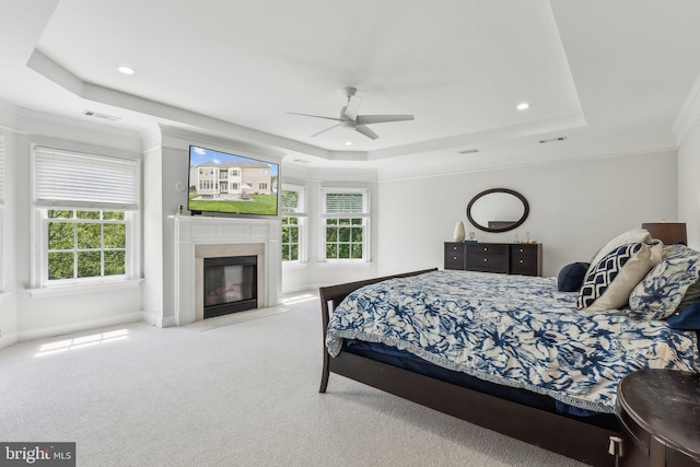 carpeted bedroom featuring a raised ceiling, crown molding, multiple windows, and visible vents