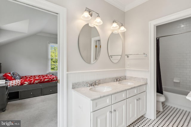 bathroom with toilet, ornamental molding, double vanity, and a sink