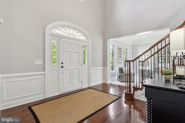 entrance foyer with stairway, wainscoting, and dark wood-type flooring