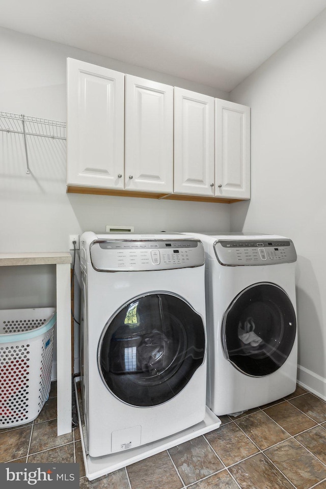 clothes washing area featuring cabinet space, washing machine and dryer, and baseboards