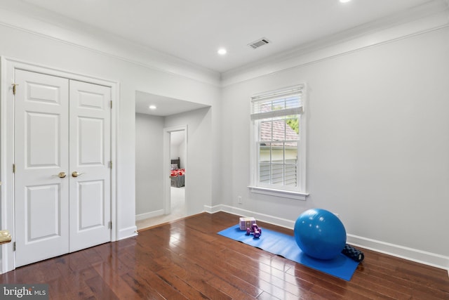 exercise area with crown molding, visible vents, baseboards, and hardwood / wood-style floors