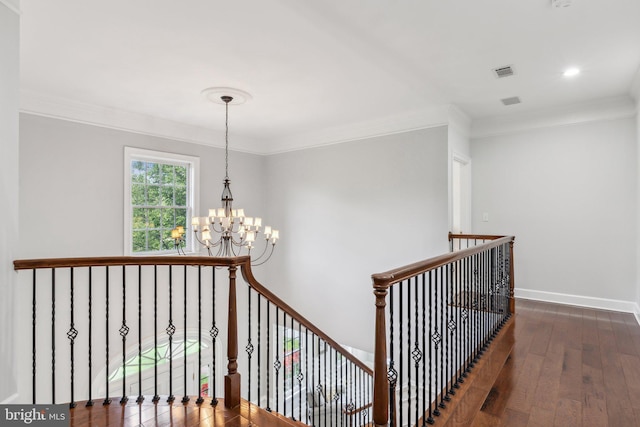 staircase with an inviting chandelier, wood-type flooring, crown molding, visible vents, and baseboards