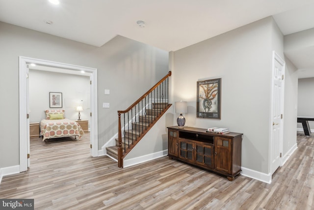 interior space with light wood-type flooring, stairway, and baseboards