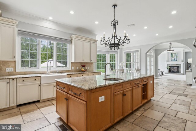 kitchen featuring recessed lighting, a sink, decorative backsplash, arched walkways, and a kitchen island with sink
