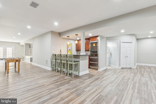 kitchen featuring a breakfast bar area, baseboards, light wood-style floors, a peninsula, and dark countertops