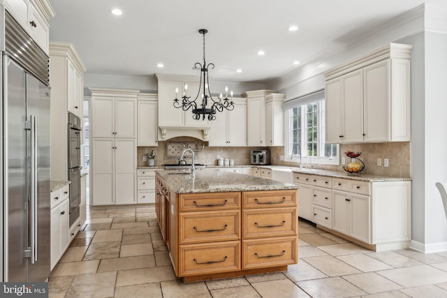 kitchen featuring appliances with stainless steel finishes, a chandelier, ornamental molding, and a sink