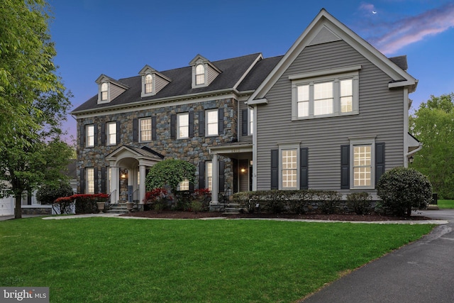 colonial house with stone siding and a front yard