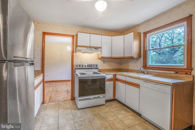 7423 Phelps Rd, Hanover, MD 21076 - kitchen featuring white appliances, under cabinet range hood, a sink, white cabinetry, and light countertops