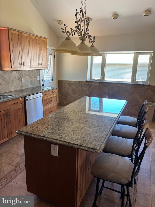 kitchen with lofted ceiling, tasteful backsplash, dark stone countertops, a breakfast bar, and dishwasher