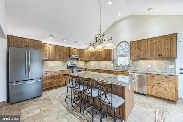 809 W 3rd Ave, Runnemede, NJ 08078 - kitchen featuring appliances with stainless steel finishes, a sink, under cabinet range hood, a breakfast bar area, and high vaulted ceiling