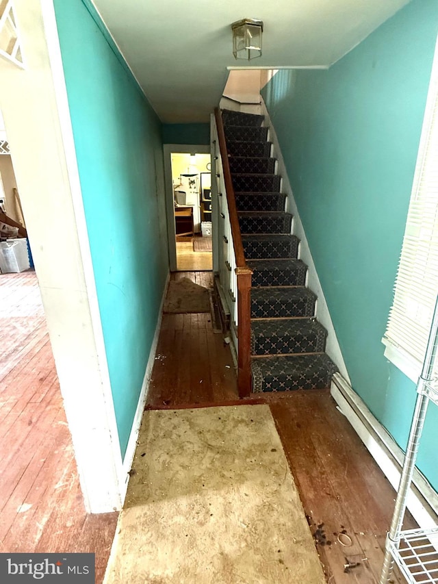 stairs with baseboards, hardwood / wood-style floors, visible vents, and a baseboard heating unit