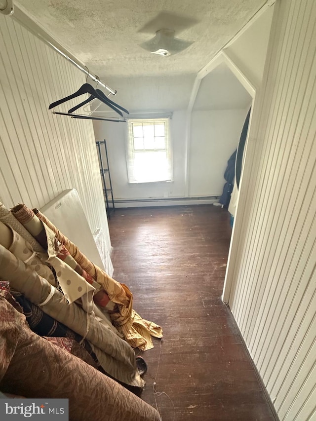 additional living space with baseboard heating, wood-type flooring, a textured ceiling, and vaulted ceiling