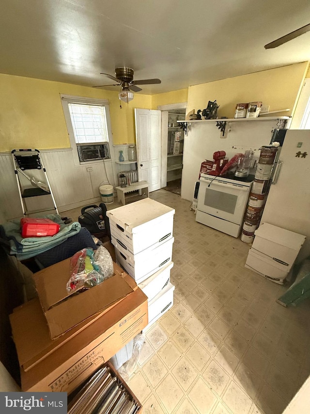 kitchen with a ceiling fan, white range with electric cooktop, cooling unit, light floors, and wainscoting