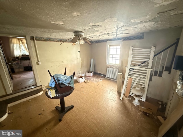 interior space with a ceiling fan, radiator, and a textured ceiling