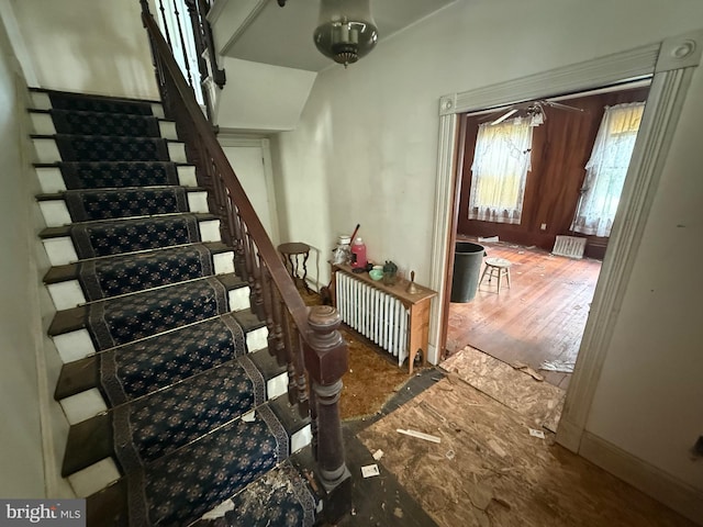 stairway featuring wood finished floors, baseboards, and radiator heating unit