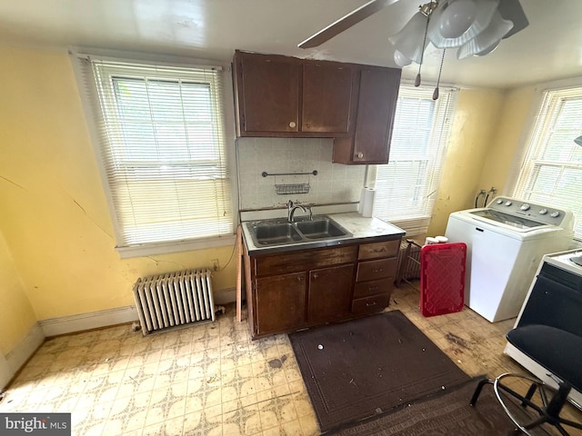 kitchen featuring a sink, radiator, separate washer and dryer, baseboards, and backsplash