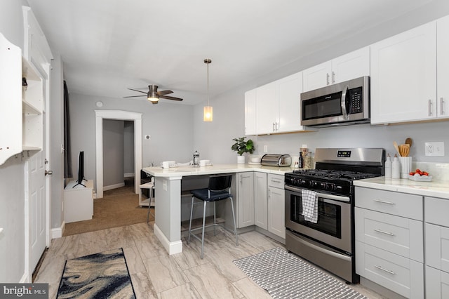 442 Poplar St, Lancaster, PA 17603 - kitchen featuring stainless steel appliances, a peninsula, ceiling fan, white cabinets, and decorative light fixtures
