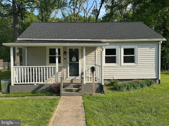 bungalow-style house with a front yard, a porch, and roof with shingles