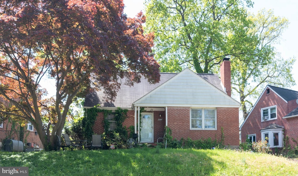 view of front facade with a front lawn, brick siding, and a chimney
