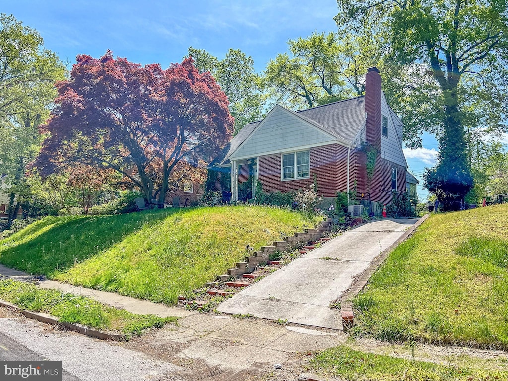 view of side of home with brick siding, a chimney, and stairs