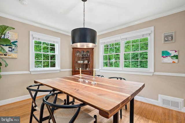dining area with baseboards, hardwood / wood-style flooring, crown molding, and plenty of natural light