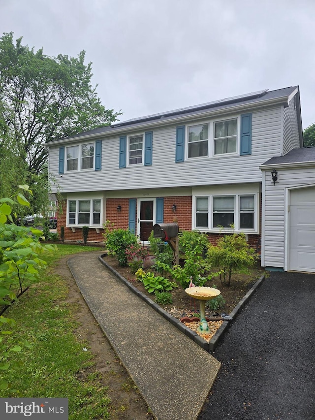 colonial house featuring brick siding and a garage