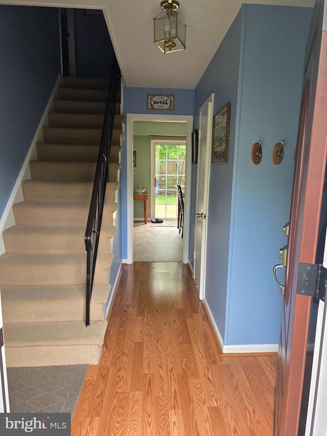 interior space featuring baseboards, stairway, and wood finished floors