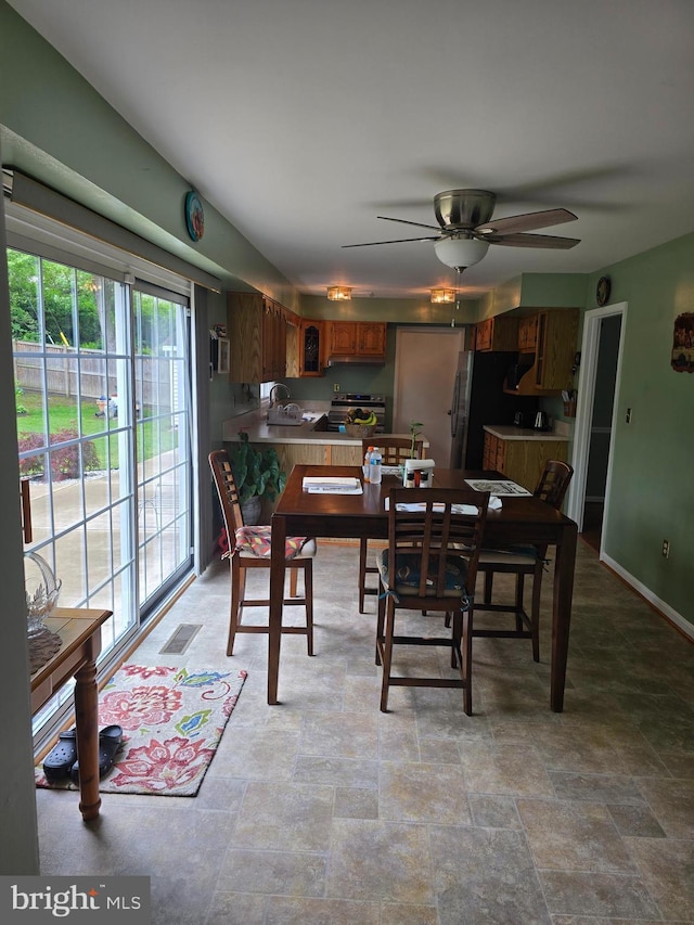 dining area featuring visible vents, baseboards, a ceiling fan, and stone finish floor