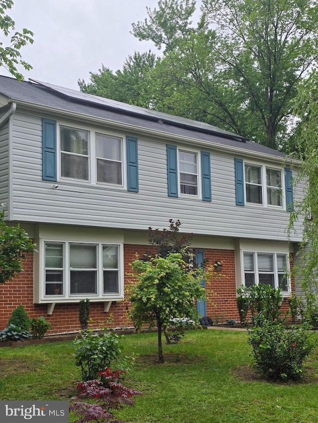 colonial home with brick siding and a front yard