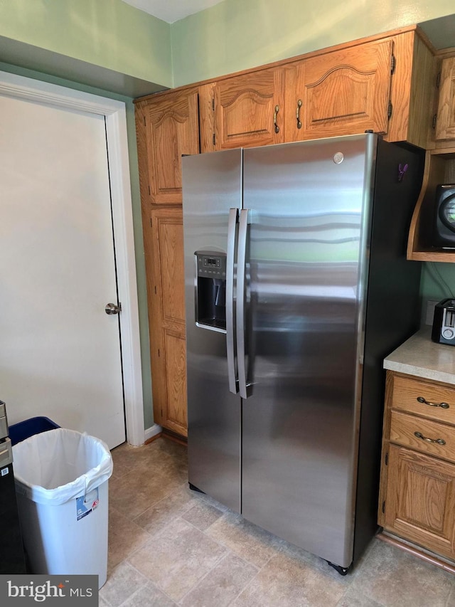 kitchen featuring brown cabinetry, light countertops, and stainless steel fridge with ice dispenser