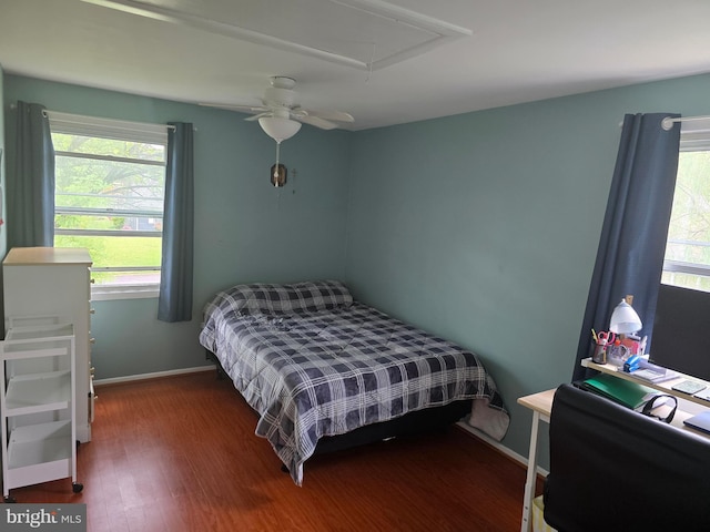 bedroom with multiple windows, attic access, wood finished floors, and baseboards