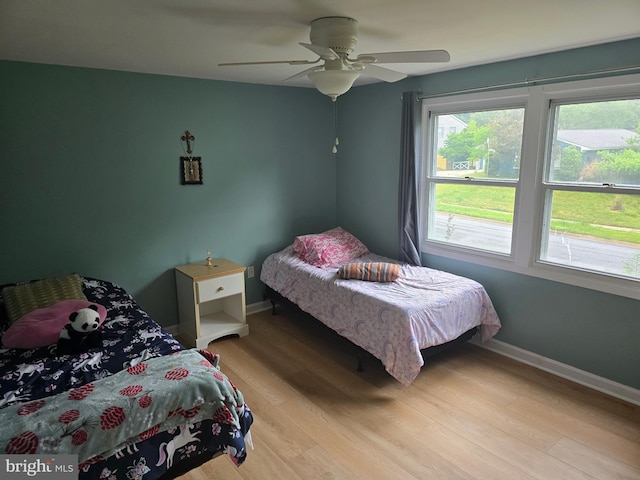 bedroom featuring light wood-style flooring, baseboards, and a ceiling fan