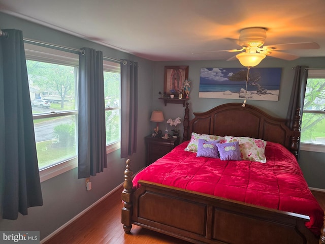 bedroom with baseboards, multiple windows, and wood finished floors