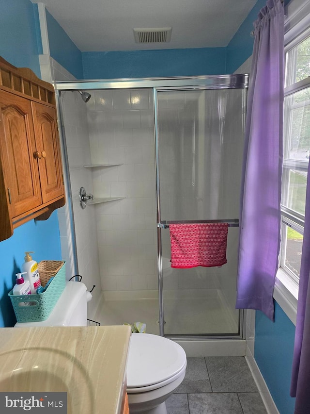 bathroom featuring toilet, vanity, visible vents, tile patterned floors, and a shower stall