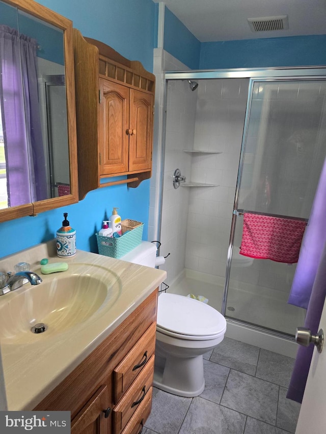 bathroom featuring toilet, a stall shower, tile patterned floors, visible vents, and vanity